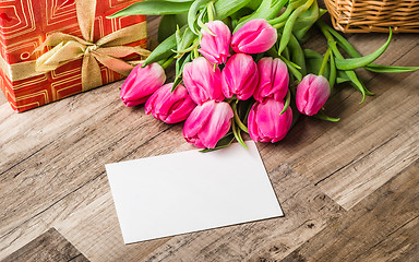 Image showing Beautiful bouquet from pink tulips and a gift on a table