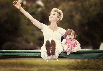 Image showing mother and little daughter swinging at backyard