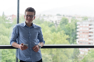 Image showing Businessman Standing In A Modern Building Near The Window With P