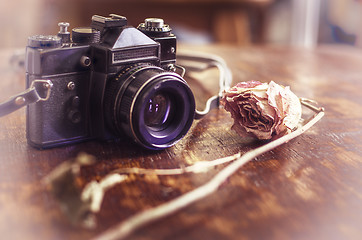 Image showing Retro photo camera and dry rose on a wooden table