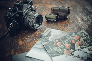 Image showing Retro photo camera, film and old photos on the table