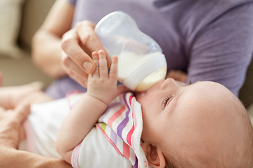 Image showing close up of father feeding baby from bottle