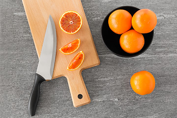 Image showing close up of oranges and knife on cutting board