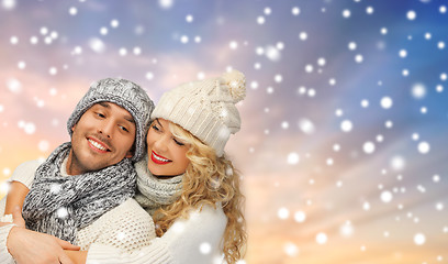 Image showing smiling couple in sweaters over snow background