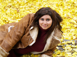 Image showing young plus-size model with yellow fall leaves and jacket