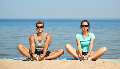 Image showing couple stretching legs on beach