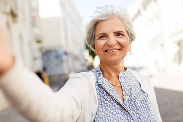 Image showing happy senior woman taking selfie on city street