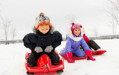 Image showing happy little kids sliding down on sleds in winter