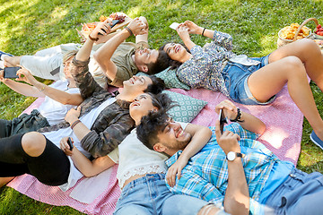 Image showing friends with smartphones chilling at summer park