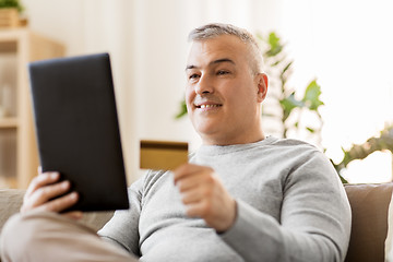 Image showing man with tablet pc and credit card on sofa at home