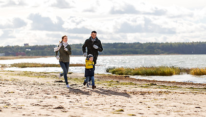 Image showing happy family running along autumn beach