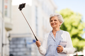 Image showing happy senior woman taking selfie on city street