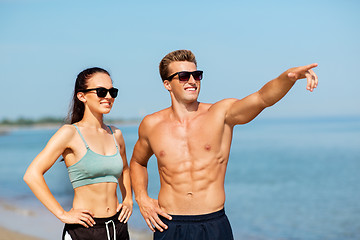 Image showing happy couple in sports clothes and shades on beach