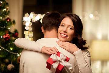 Image showing happy couple with christmas gift hugging at home
