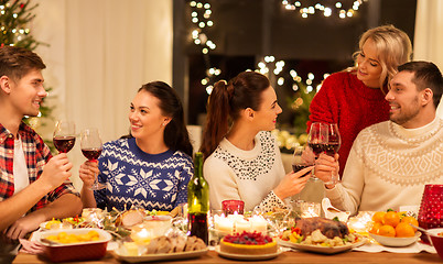 Image showing happy friends drinking red wine at christmas party