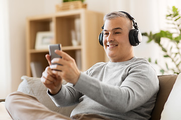 Image showing man with smartphone and headphones at home