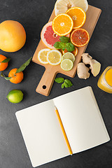 Image showing close up of fruits and notebook on slate table top