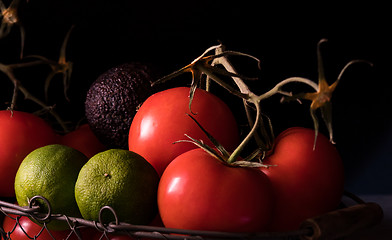 Image showing big red and ripe tomatoes in an old basket on black background