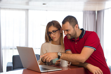 Image showing couple drinking coffee and using laptop at home