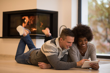 Image showing multiethnic couple using tablet computer on the floor