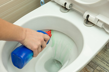 Image showing The hand puts a liquid detergent under the rim of the toilet bowl