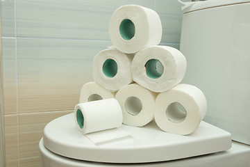 Image showing The pyramid of toilet rolls lies on the lid of the toilet bowl