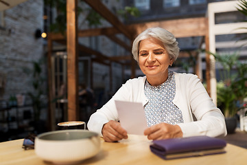 Image showing senior woman with bill for coffee at street cafe