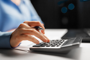 Image showing businesswoman with calculator at night office