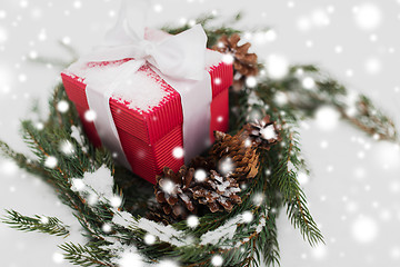 Image showing christmas gift and fir wreath with cones on snow