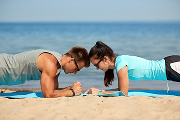 Image showing couple doing plank exercise on summer beach