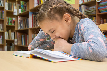 Image showing Girl laughing while reading a book in the library