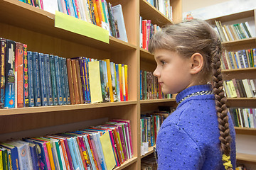Image showing The girl chooses books in the library