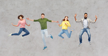 Image showing happy people or friends jumping in air over gray
