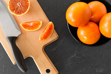 Image showing close up of oranges and knife on cutting board