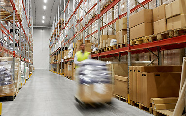 Image showing worker carrying loader with goods at warehouse