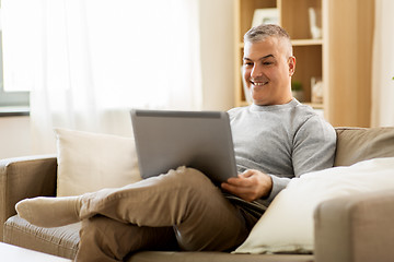 Image showing man with laptop computer sitting on sofa at home