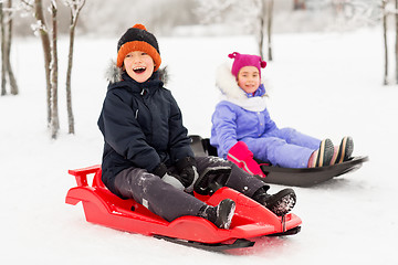 Image showing happy little kids sliding on sleds in winter