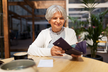 Image showing senior woman with wallet paying bill at cafe