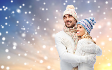 Image showing happy couple in winter clothes hugging over snow