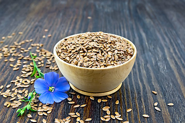 Image showing Flaxen brown seed in bowl with blue flower on board