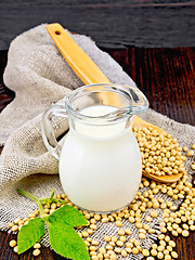 Image showing Milk soy in jug with spoon and leaf on dark board