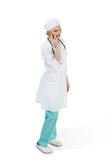 Image showing Beautiful young woman in white coat posing at studio. Full length studio shot isolated on white.