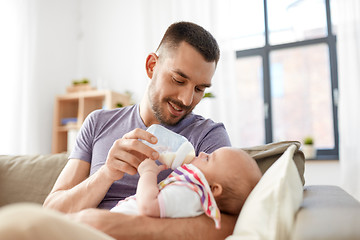 Image showing father feeding baby daughter from bottle at home