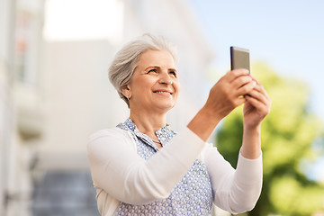 Image showing senior woman photographing by smartphone in city