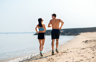 Image showing couple in sports clothes running along on beach