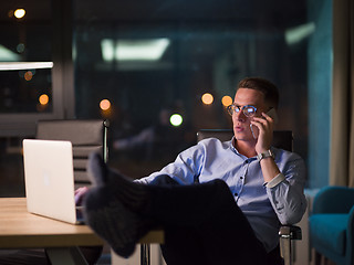 Image showing businessman using mobile phone in dark office