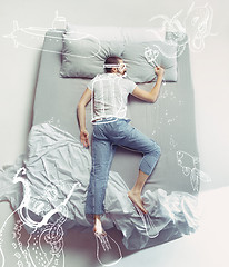 Image showing Top view photo of young man sleeping in a big white bed and his dreams