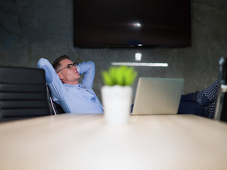 Image showing businessman sitting with legs on desk at office