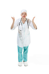 Image showing Beautiful young woman is sending an air kiss in white coat posing at studio. Full length studio shot isolated on white.