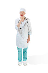 Image showing Beautiful young woman is whispering a secret in white coat posing at studio. Full length studio shot isolated on white.